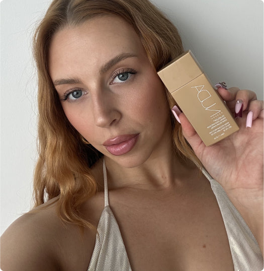 Woman holding a beige NUDA product against a white background
